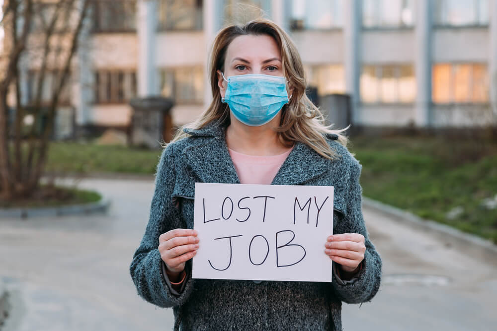 Woman holding sign indicating she has lost her job