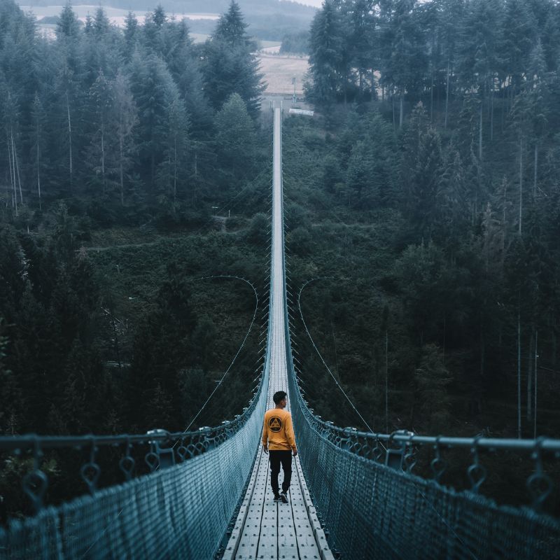 Man Walking On Simple Suspension Bridge