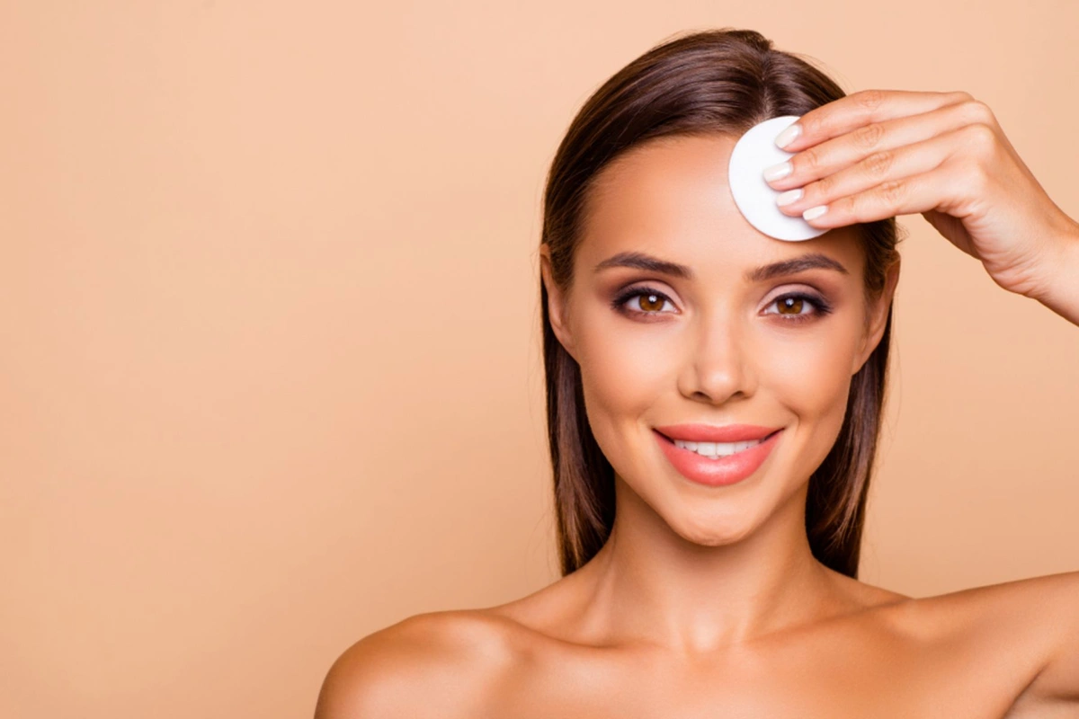 Woman cleansing her forehead with a micellar water pad