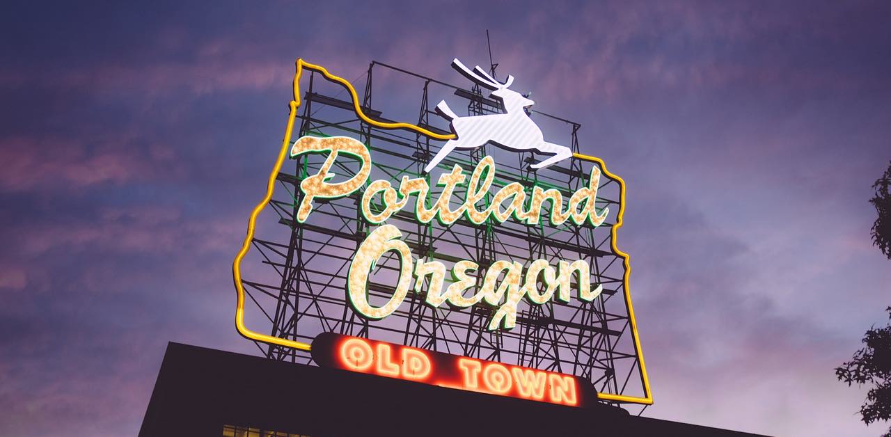 A neon sign with a deer and Portland, Oregon illuminated