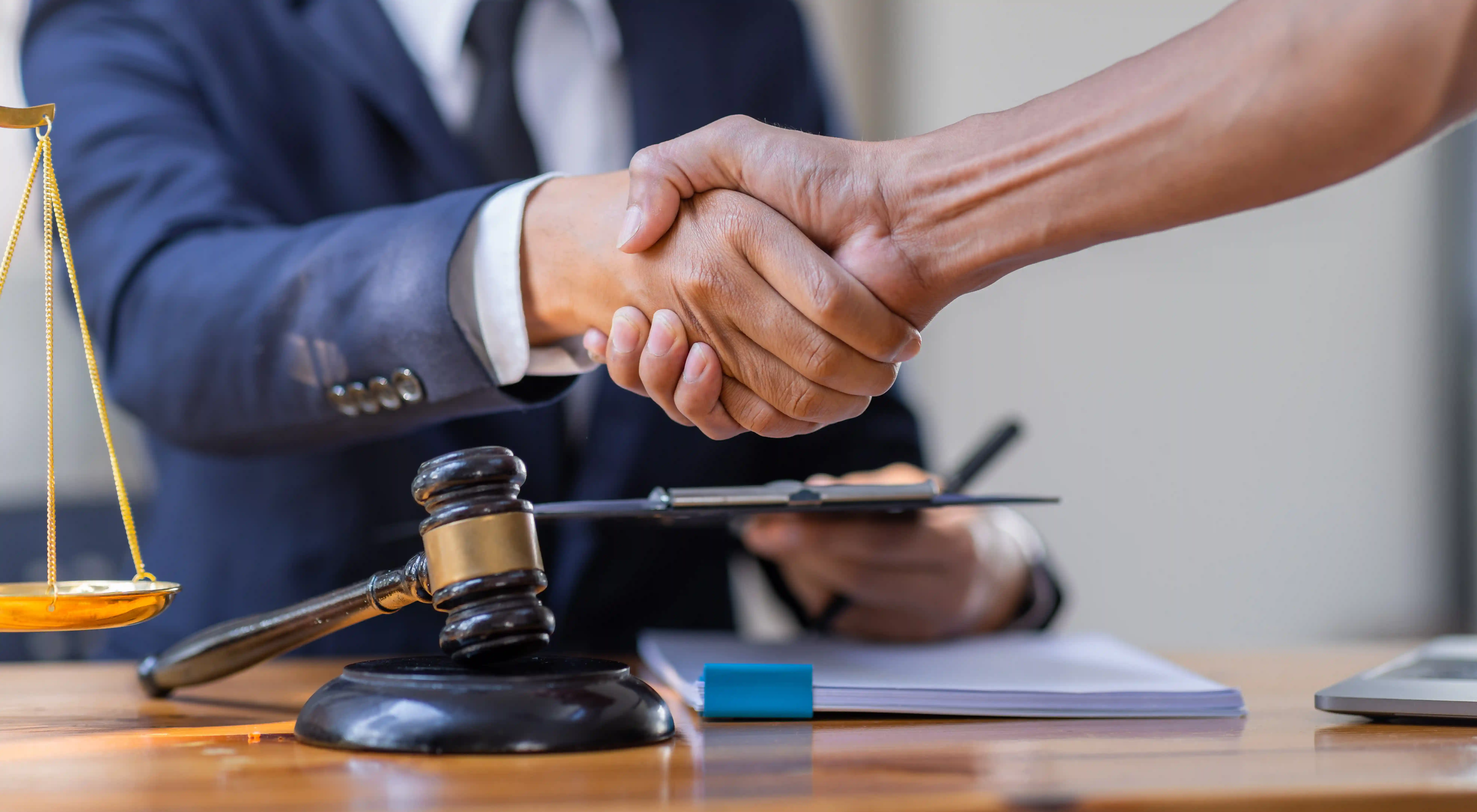 Business handshake with gavel and justice scales representing legal compliance verification in global talent sourcing