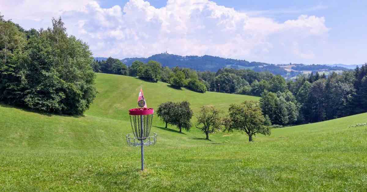Disc golf basket on rolling green hills