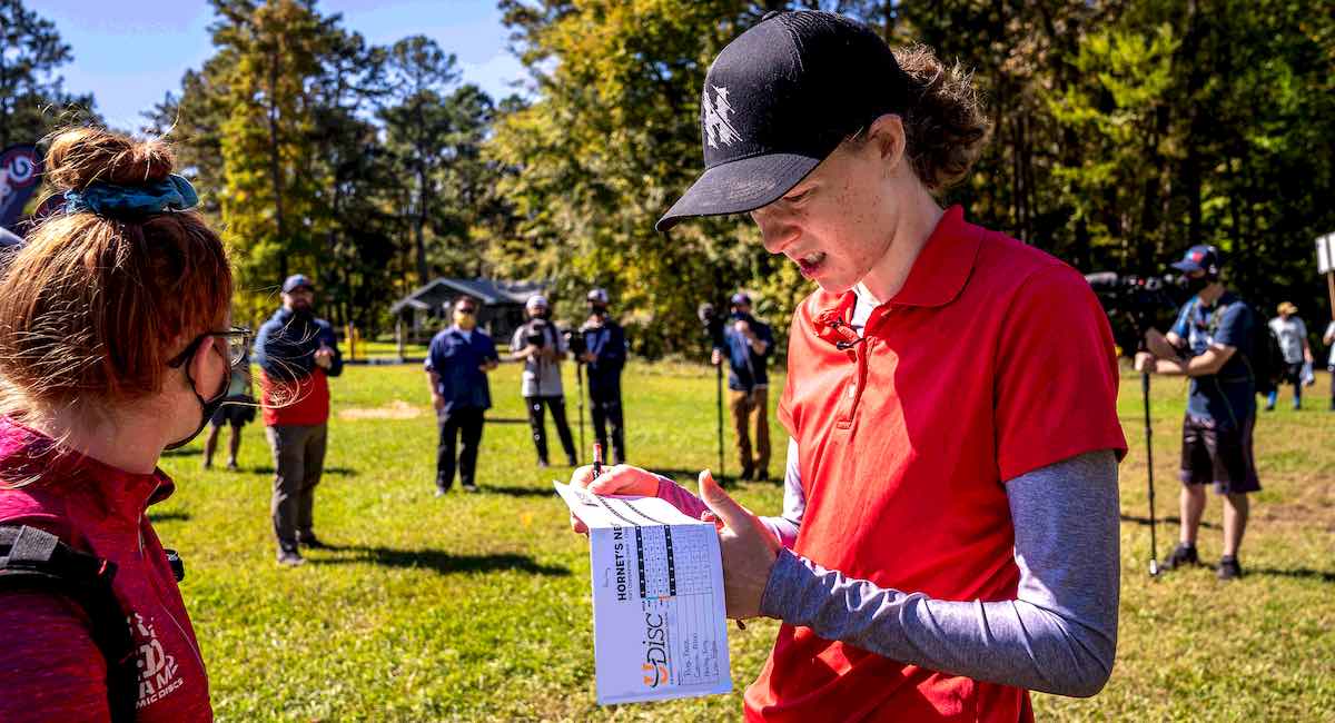 A young woman looks confusedly at a disc golf scorecard