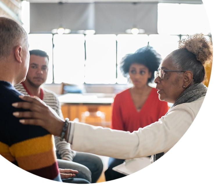 Senior woman comforting a mature man in group therapy at a coworking