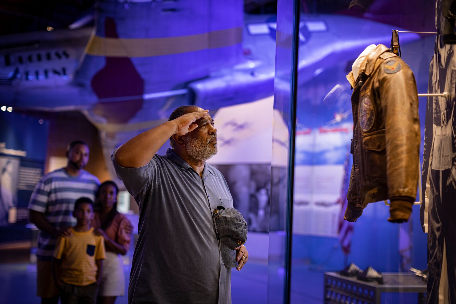 Man saluting Tuskegee Airman bomber jacket at museum