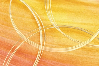 coils of wire used for jewelry making on top of a pained yellow and orange background