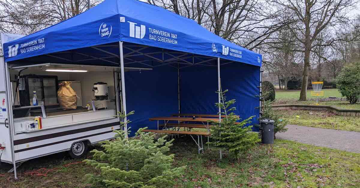 A food cart with a shelter and picnic tables in front of it in a park
