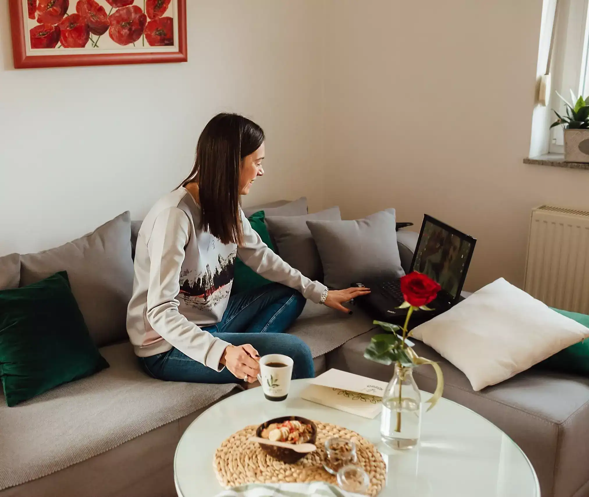 Woman checking laptop in sofa having coffee