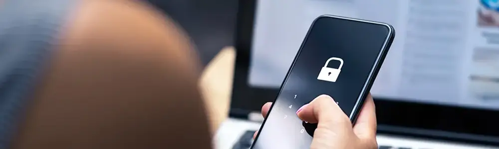 person using phone with lock icon on it in front of laptop