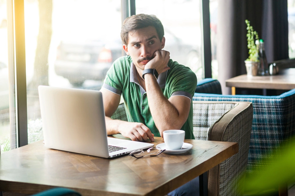 A man thinking hard while looking at his laptop