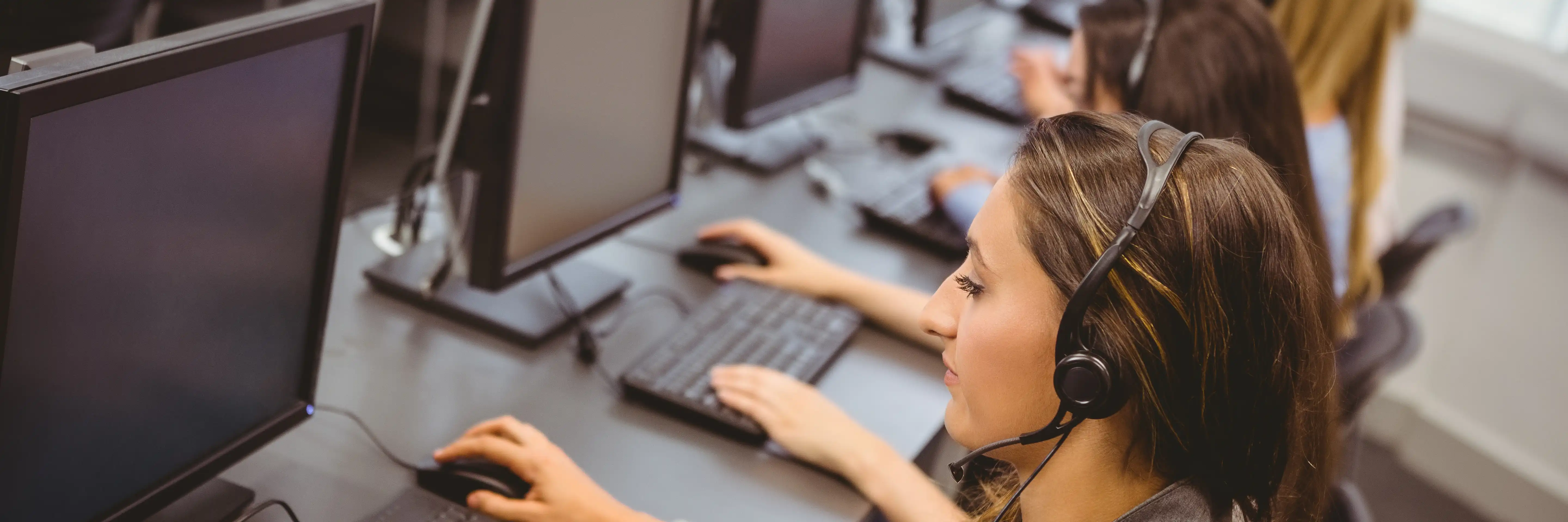 Woman working at a desktop with her head piece on.