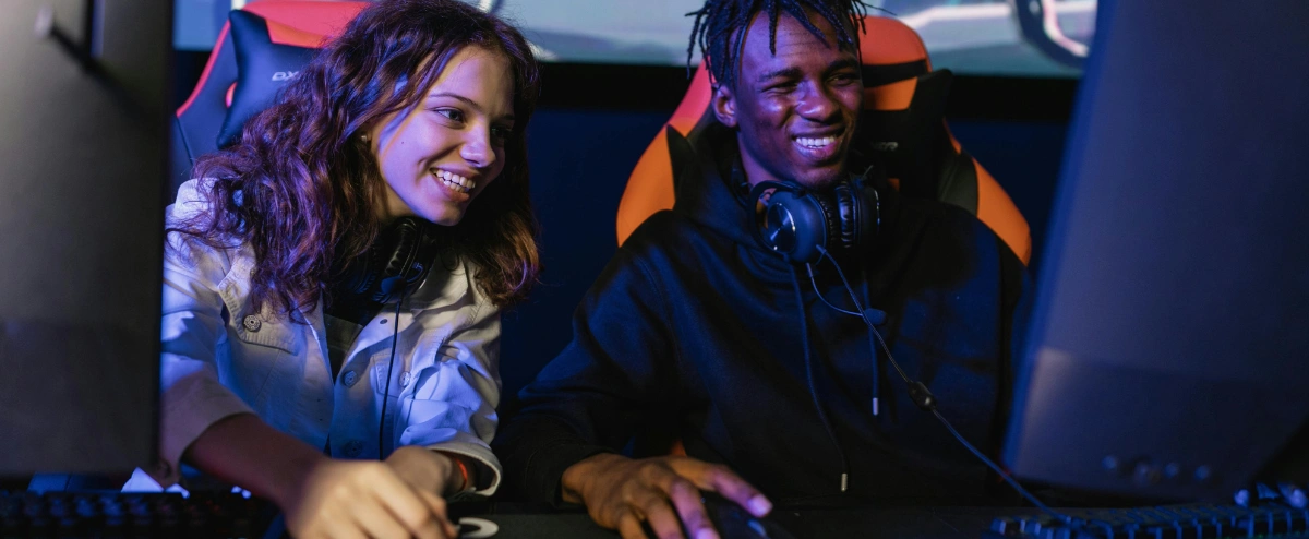 Two friends playing video games on separate PCs.