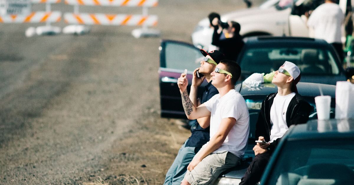 people lounging in car with eclipse glasses looking at the sky