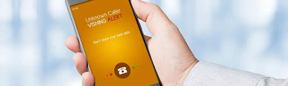 hand holding phone with incoming call and vishing warning message