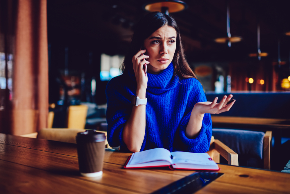 Woman talking on the phone at a table with a coffee cup
