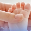 mãos de um adulto segurando o pé de um bebê, cuidados com a saúde infantil, acompanhamento pediátrico