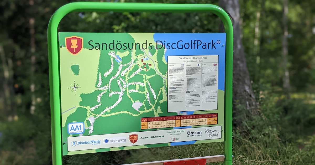 An information board (mostly green) showing the layout of Sandösunds DiscGolfPark