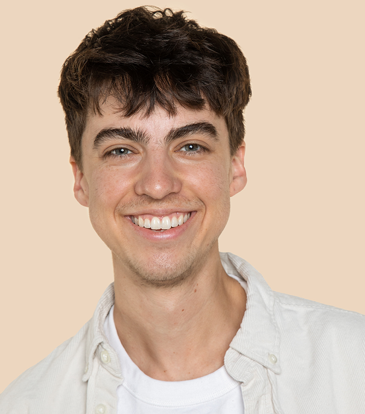 Person smiling in front of a beige background