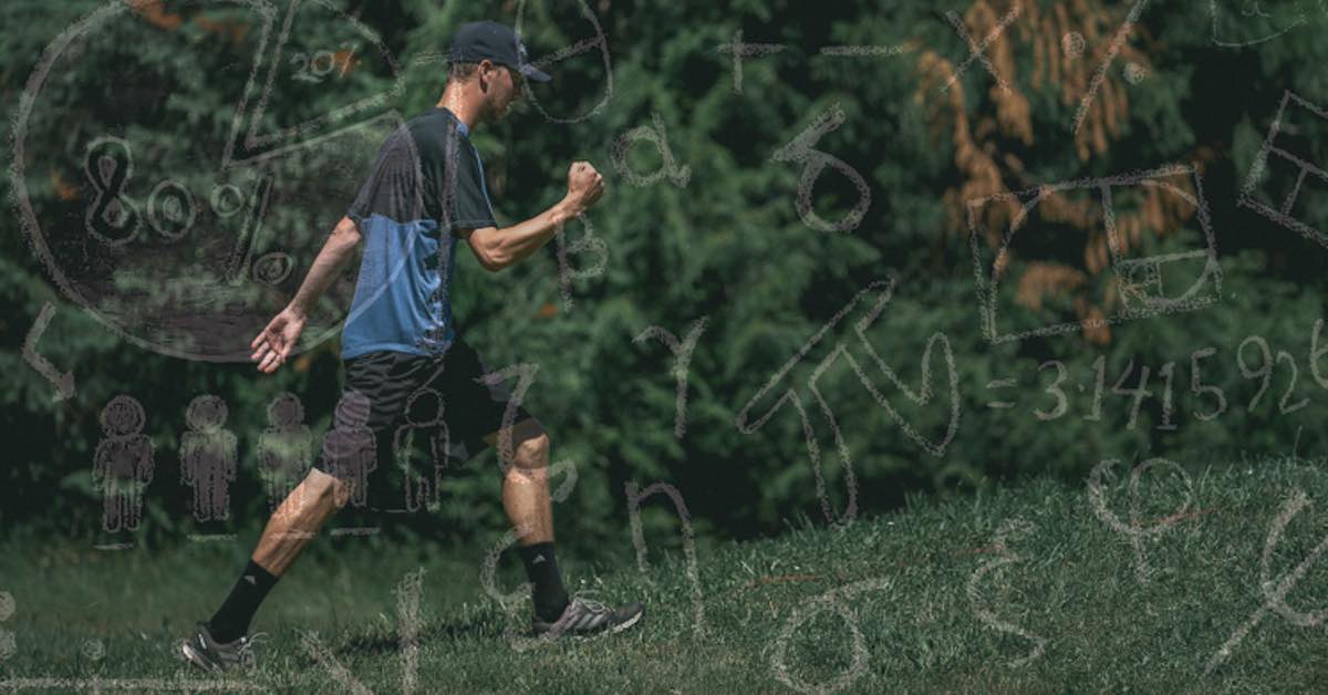A man in shorts pumps his fist as he walks on a grassy area in front of trees
